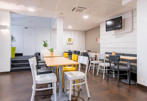 Un comedor con mesas y sillas y un televisor de pantalla plana. en B&B HOTEL Valenciennes Sud 3 étoiles, en Valenciennes
