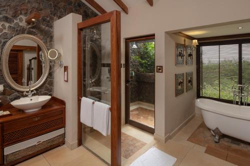 een badkamer met een bad, een douche en een wastafel bij Ngorongoro Oldeani Mountain Lodge in Oldeani