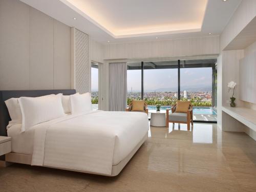 um quarto com uma cama branca e uma grande janela em Grand Mercure Lampung em Bandar Lampung