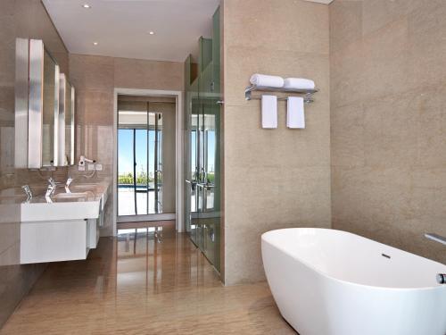 La salle de bains est pourvue d'une baignoire blanche et d'un lavabo. dans l'établissement Grand Mercure Lampung, à Bandar Lampung