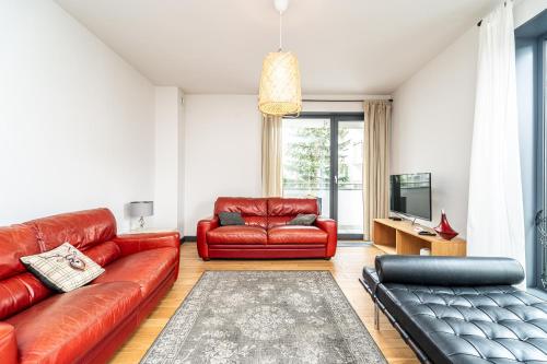 sala de estar con muebles de cuero rojo y TV en RentPlanet - Kamienica Retmana en Cracovia