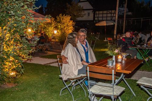 two women sitting at a table in a garden at night at Deutsches Haus Hotel Restaurant Gastwirtschaft Biergarten am Radweg Bermuthshain in Bermuthshain