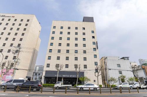 a large white building with cars parked in front of it at Sota stay Hotel in Seoul