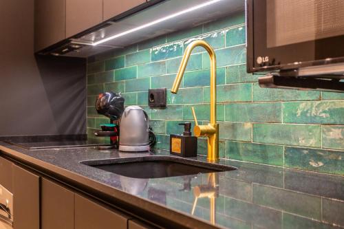 - un comptoir de cuisine avec évier et carrelage vert dans l'établissement Suite Deluxe Valencia - AIORA Apartments, à Valence