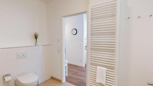 a bathroom with a toilet and a clock on the wall at Südkap G-06 in Pelzerhaken