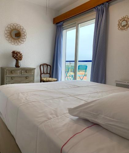 une chambre avec un grand lit blanc avec une fenêtre dans l'établissement Appartement moderne, mer à 50m, au Barcarès