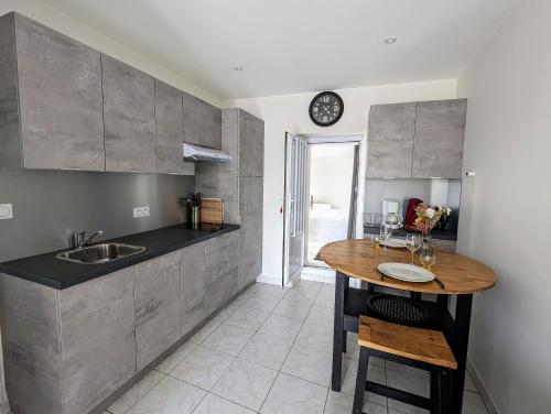 une cuisine avec une table et une horloge au mur dans l'établissement Pied-à-terre proche du centre et commodités, à Pornic