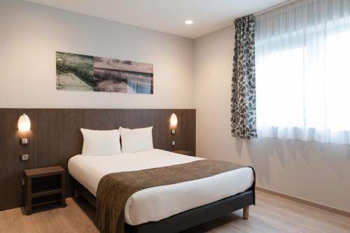 a hotel room with a bed and a window at The Originals City, L'Haut' Aile, Coquelles-Calais Tunnel s/Manche L'HAUTAILE in Coquelles