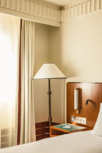 a bedroom with a bed and a lamp and a window at Hôtel Des Grands Voyageurs in Paris