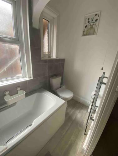 a white bathroom with a tub and a toilet at Spacious Ashley Cross Flat in Parkstone