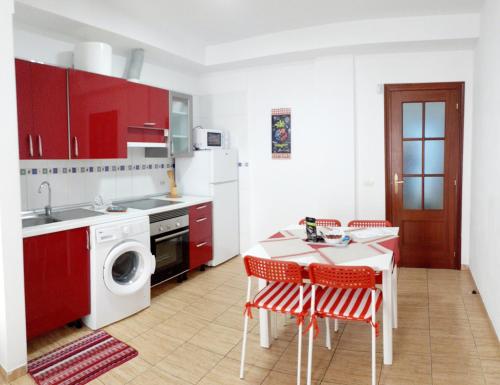una cocina con armarios rojos y una mesa con sillas. en Appartamento Mochiri - San Isidro, en San Isidro
