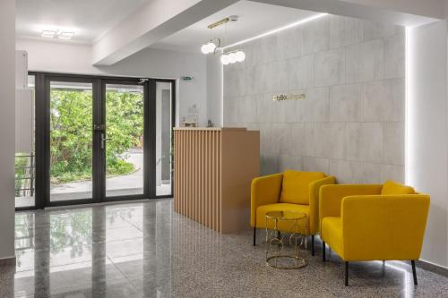 奧托佩尼的住宿－Otopeni Suites by CityBookings，一间设有两张黄色椅子和一张桌子的等候室