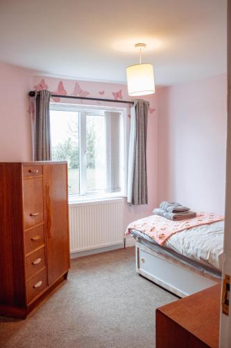 a bedroom with a bed and a dresser and a window at Family Getaway at Working Farm in Church Fenton