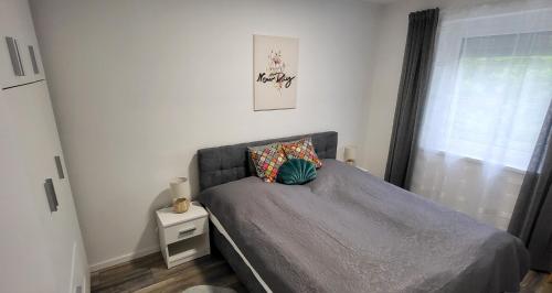 ein kleines Schlafzimmer mit einem Bett und einem Fenster in der Unterkunft Juhar 1 Apartman in Kőszeg