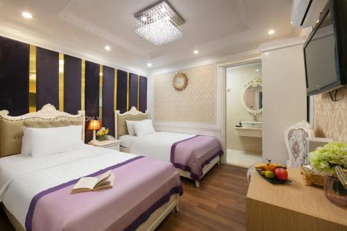 ein Hotelzimmer mit 2 Betten und einem TV in der Unterkunft The Silk Grand Premium Hotel & Spa in Hanoi