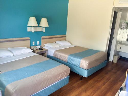 two beds in a room with blue walls and wooden floors at Motel 6 Fredericksburg, Va - North in Fredericksburg