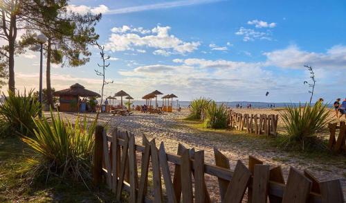 a sandy beach with umbrellas and a wooden fence at Mobil Home Premium 3 ch 6 pers Camping Mayotte 5* in Biscarrosse