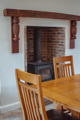 a fireplace in a dining room with a wooden table at Family Getaway at Working Farm in Church Fenton