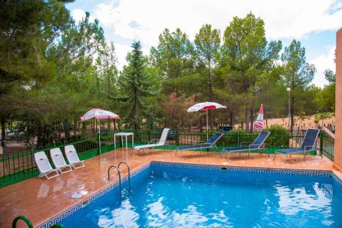 a swimming pool with lounge chairs and umbrellas at La Derrubiá in Villamalea