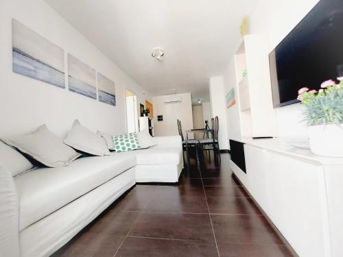 a living room with a white couch and a tv at Alojamiento Amelie con WiFi gratis in Murcia