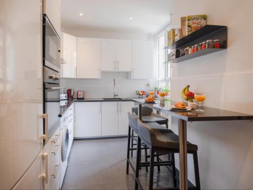 une cuisine avec des placards blancs et un bar avec des tabourets dans l'établissement Paris Palais des Congrès Residence, à Neuilly-sur-Seine