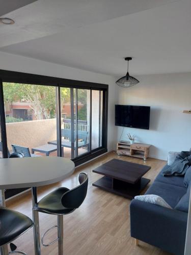 un salon avec un canapé bleu et une table dans l'établissement Appartement proche de la mer, à Perpignan