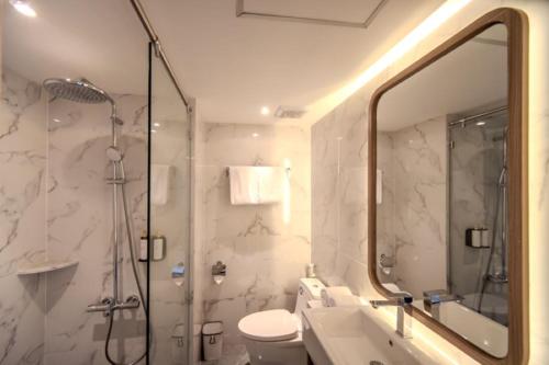 a bathroom with a shower and a toilet and a sink at Grand Altuz Hotel Yogyakarta in Seturan