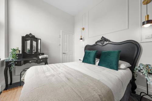 a bedroom with a bed with green pillows and a mirror at Pelican Suite - Design 1Bed Flat in Harrogate