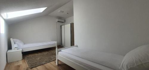 Cette chambre blanche comprend 2 lits et un miroir. dans l'établissement NG Natural Garden, à Sarajevo