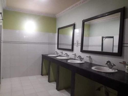 ein Badezimmer mit 3 Waschbecken und einem großen Spiegel in der Unterkunft Old Everest Hotel in Khanchikot