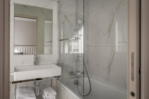 a white bathroom with a sink and a shower at Hôtel des Deux Avenues in Paris