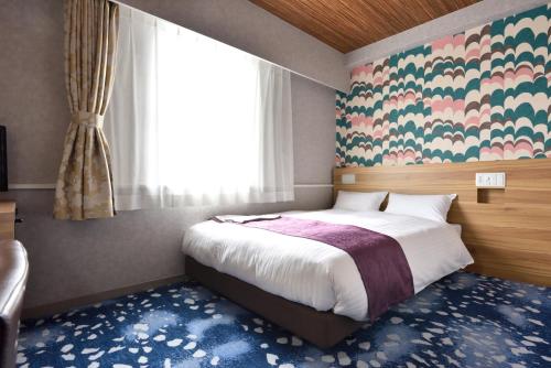 a bedroom with a bed and a large window at Smile Hotel Kushiro in Kushiro