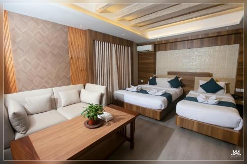 Habitación de hotel con 2 camas y sofá en Hotel Maya Boutique and Apartment, Thamel, en Katmandú