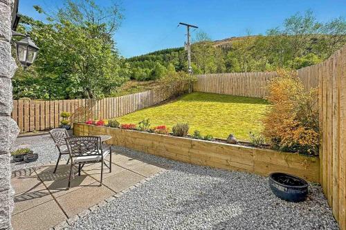 a patio with a chair and a garden with a fence at Outlander Glencoe at Creag an-t Sionnaich in Glencoe