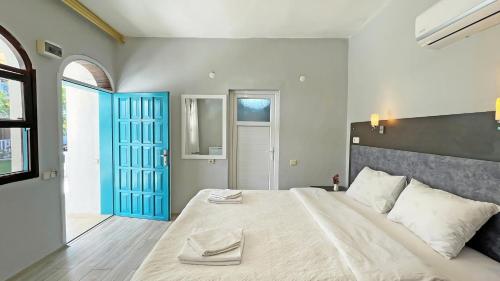 a bedroom with a large bed with a blue door at Jasmin Pansiyon Çıralı in Cıralı