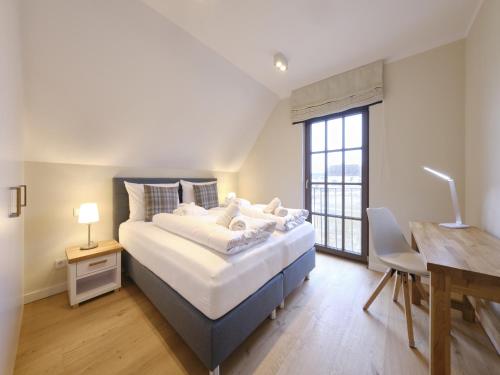 a bedroom with a bed with a desk and a window at Reetland am Meer - Luxus Reetdachvilla mit 3 Schlafzimmern, Sauna und Kamin H07 in Dranske