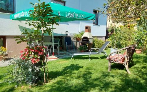 a garden with two chairs and a table and a umbrella at Apartments and Rooms Tavcar in Bled
