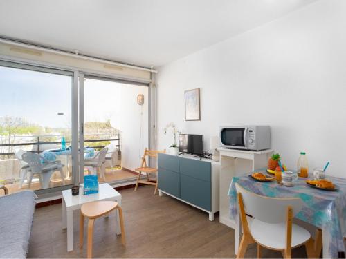 a living room with a table and a microwave at Apartment Du Soleil-3 by Interhome in La Grande Motte