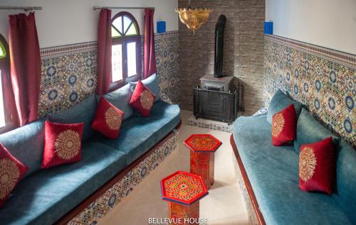 BELLEVUE HOUSE - with terrace in the heart of medina في شفشاون: غرفة معيشة مع أريكة وموقد خشبي