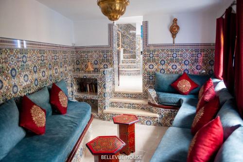 BELLEVUE HOUSE - with terrace in the heart of medina في شفشاون: غرفة معيشة مع أريكة زرقاء ووسائد حمراء