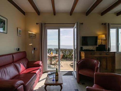 ein Wohnzimmer mit einem Sofa und einem Tisch mit Aussicht in der Unterkunft Holiday Home Les Roches - LPU 103 by Interhome in Clohars-Carnoët