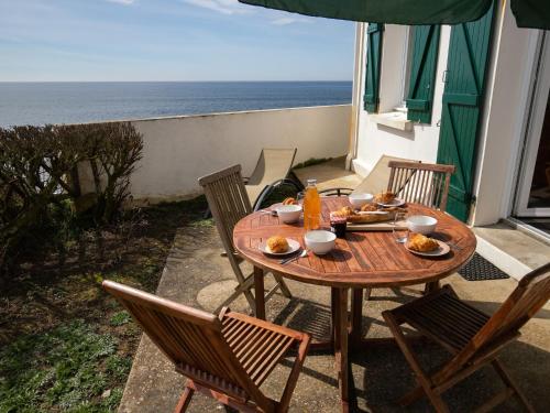 une table et des chaises en bois sur une terrasse avec l'océan dans l'établissement Holiday Home Les Roches by Interhome, à Clohars-Carnoët