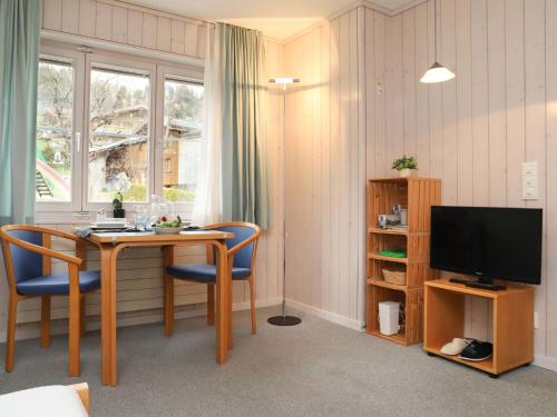 um quarto com uma mesa e cadeiras e uma televisão em Apartment Suzanne Nr- 21 by Interhome em Gstaad