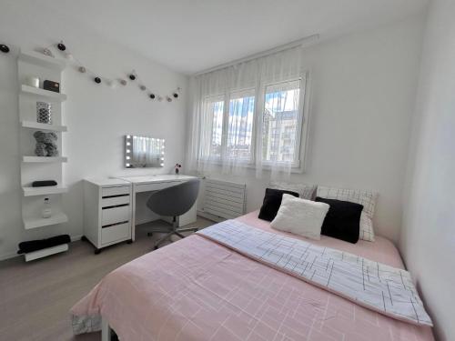 ein weißes Schlafzimmer mit einem Bett und einem Schreibtisch in der Unterkunft Appartement moderne et lumineux in Charenton-le-Pont
