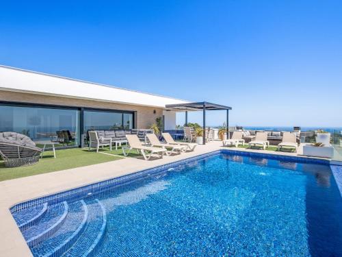 a swimming pool with chaise lounge chairs and a house at Villa Megin by Interhome in Cumbre del Sol