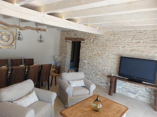 a living room with a tv and a brick wall at Bergerie du Causse in Livernon