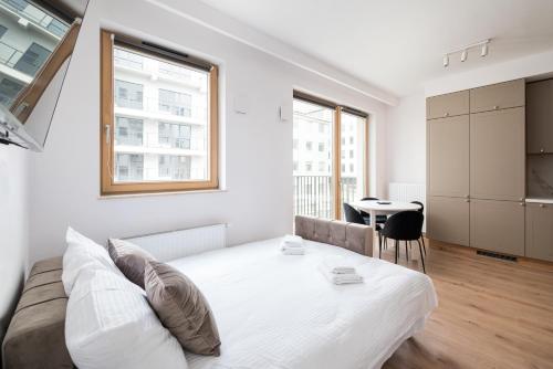 a white bedroom with a bed and a table at Wola Kolejowa Deluxe Studio in Warsaw