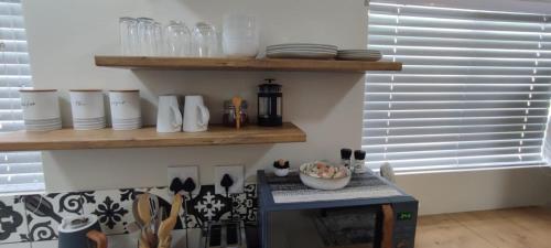 a kitchen with a counter with plates and bowls on a shelf at Lasai Accommodation in Worcester