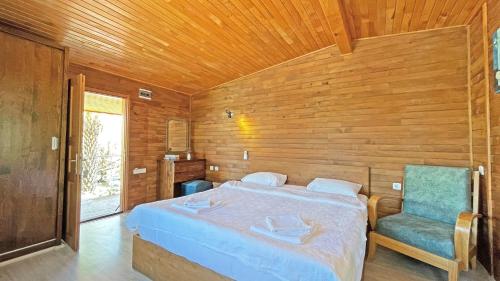 a bedroom with a bed and a blue chair at Jasmin Pansiyon Çıralı in Cıralı