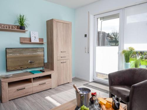 een woonkamer met een televisie en een bank bij Apartment Ankerweg-2 by Interhome in Norddeich